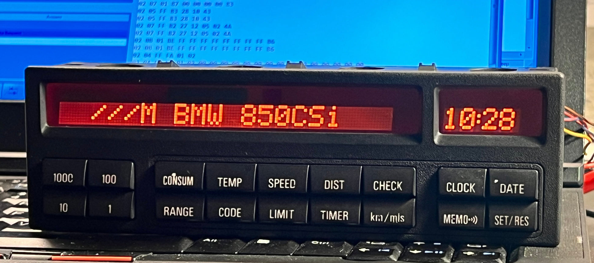 Vintage car dashboard display with digital readout in front of a computer screen