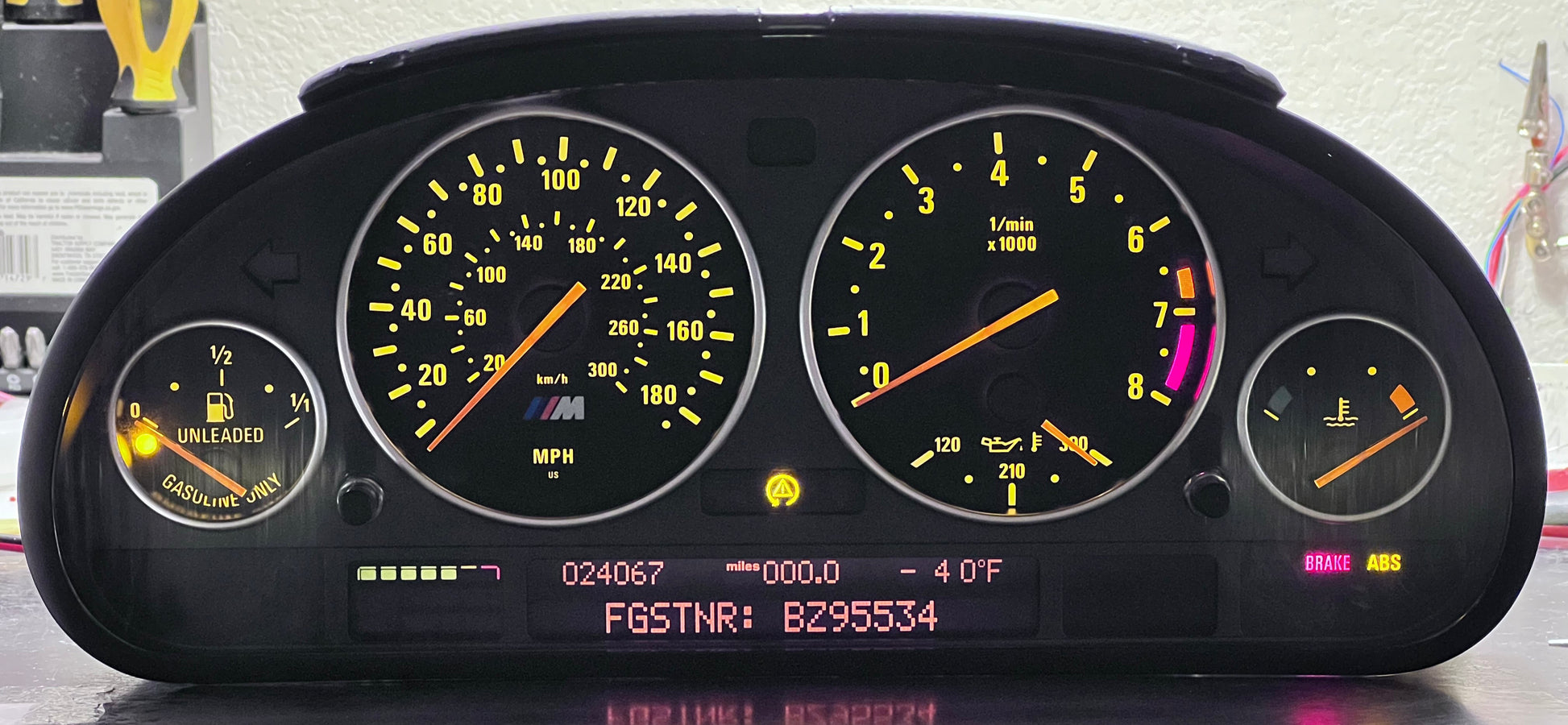 M5 dashboard with illuminated gauges on a reflective surface
